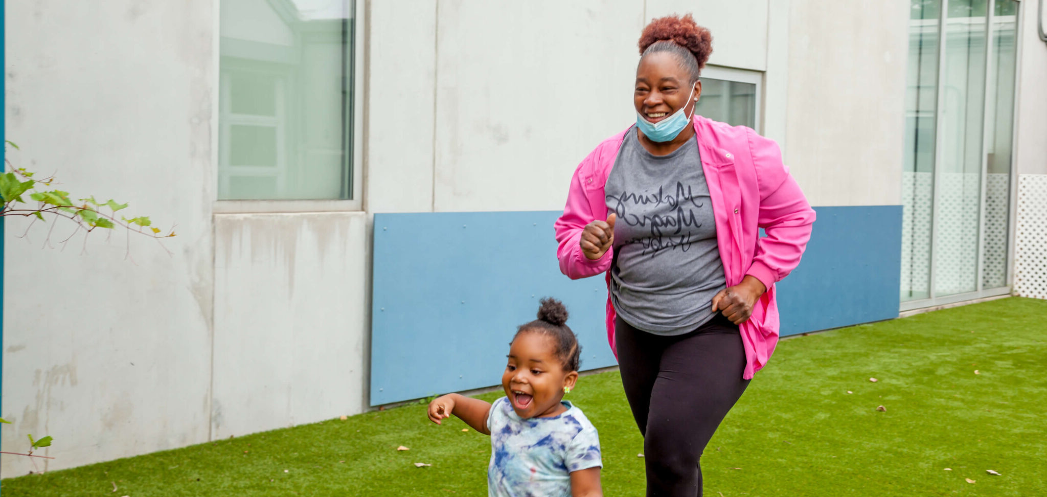 Educare teacher running with student in front of building