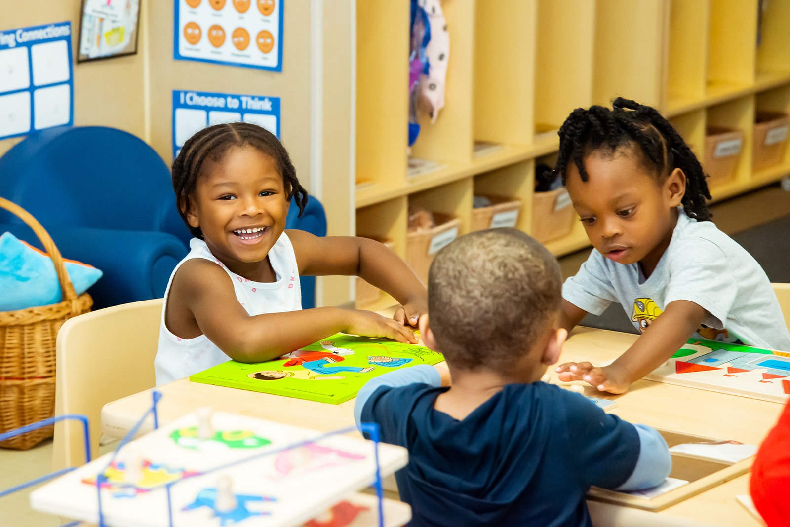 Child smiling doing a puzzle with 2 other children